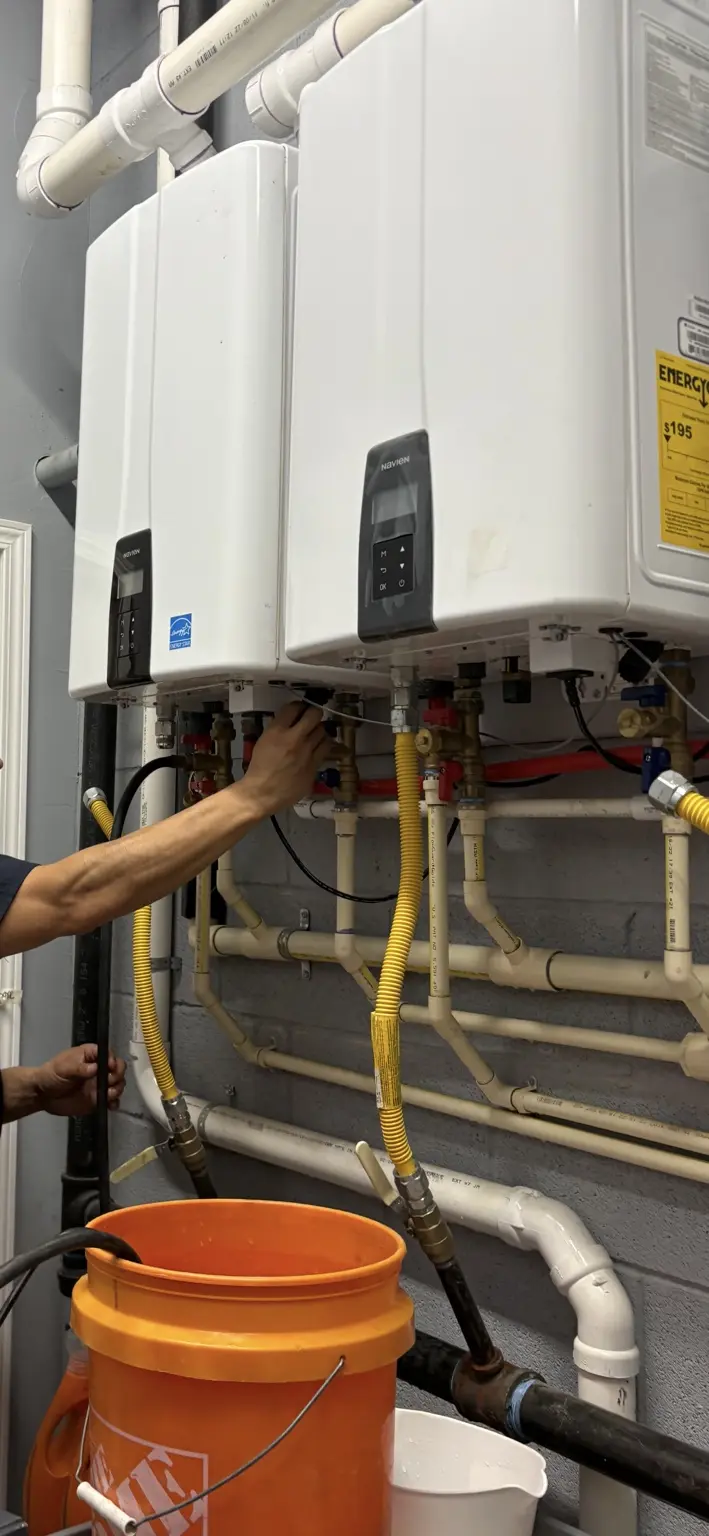 MRC Plumbing Solutions technician servicing a dual Navien tankless water heater system