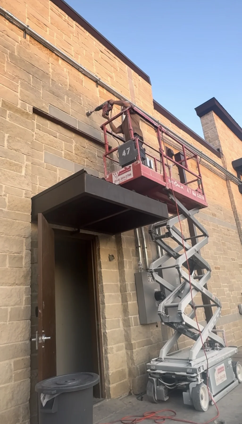 Technician accessing exterior commercial piping from a scissor lift